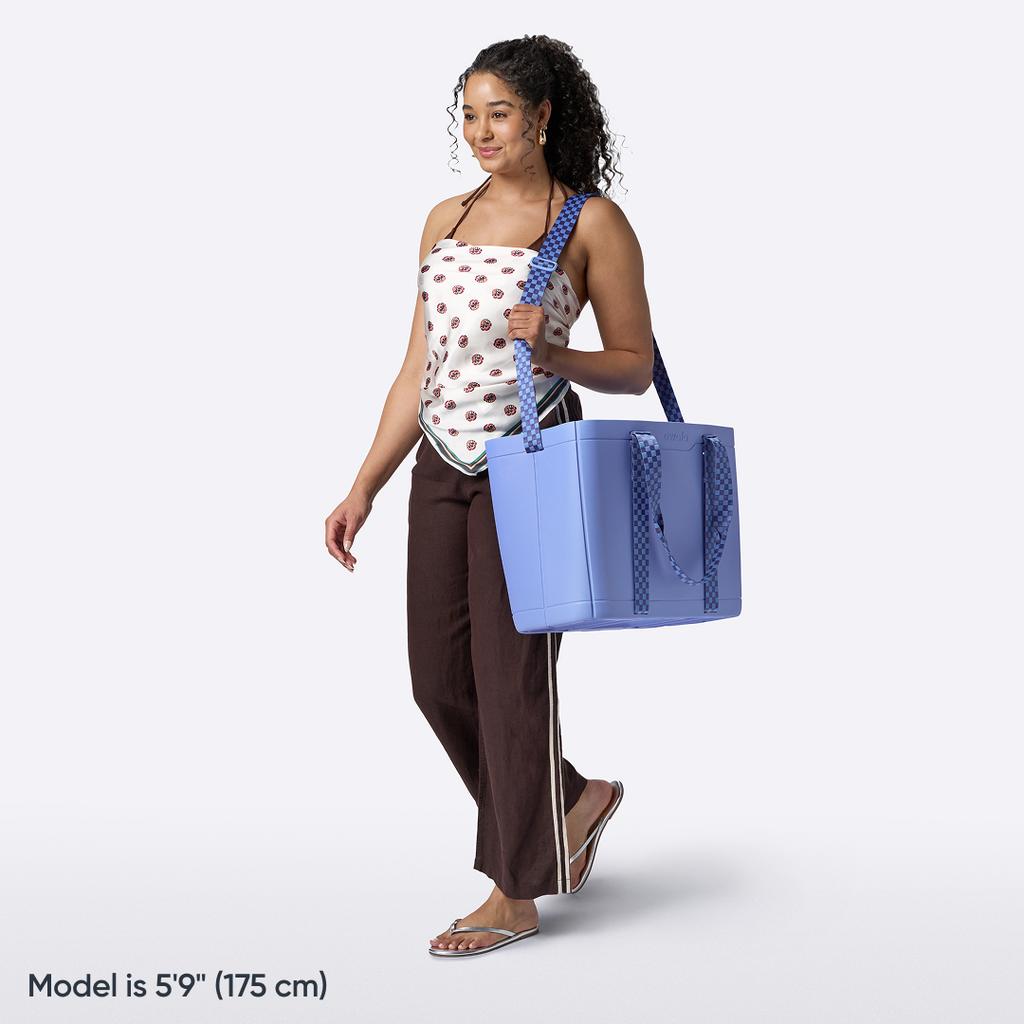 Model holding the Owala Sun-Day Collapsible Tote in Wavelength, cobalt blue with checkered strap, at the hip while carrying a rolled yoga mat